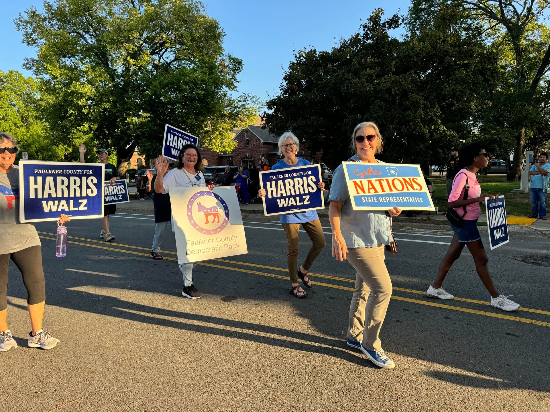 Three women holding policy-focused signs at an outdoor event
