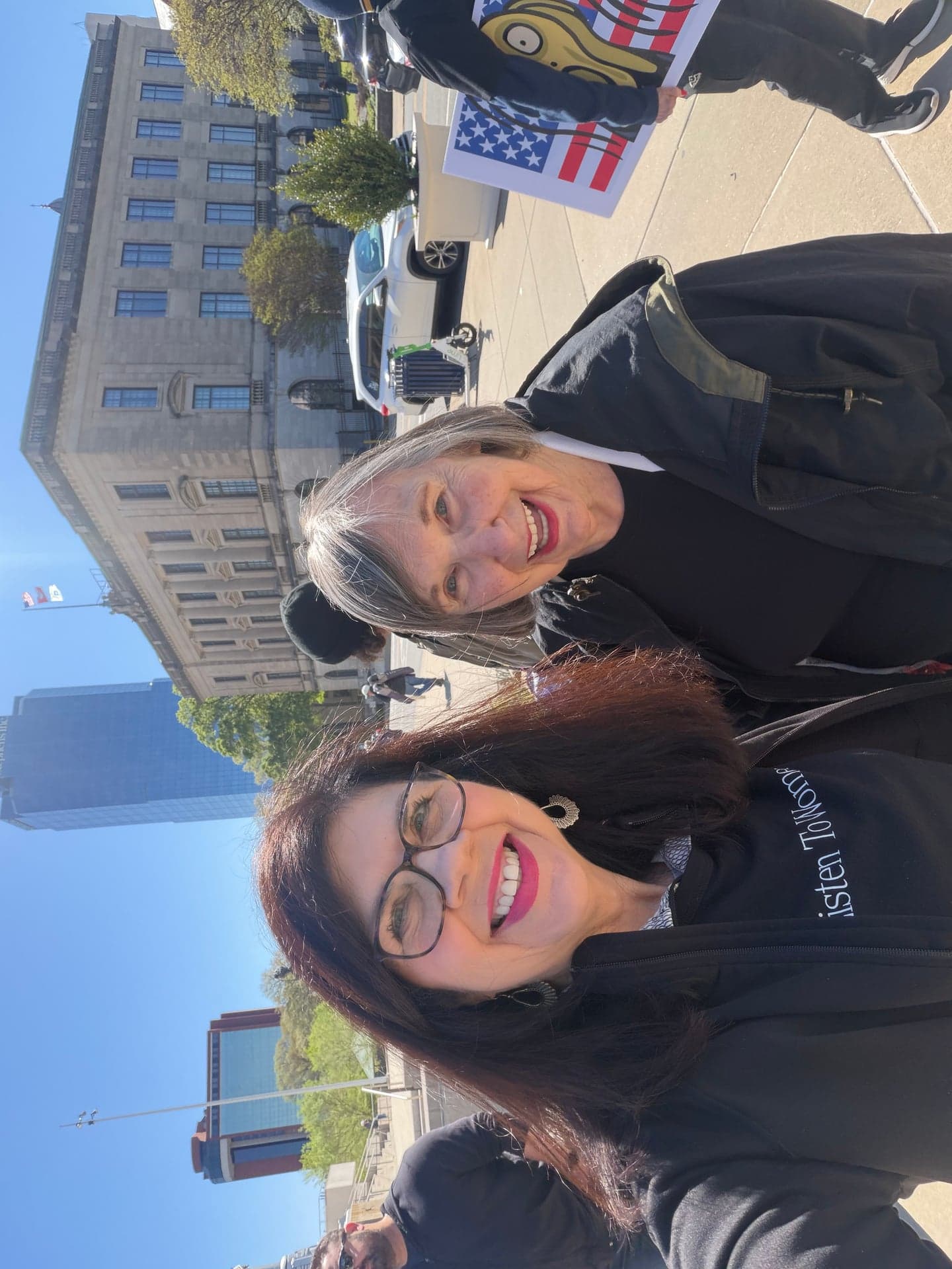 Two women at a rally with listen to women messaging
