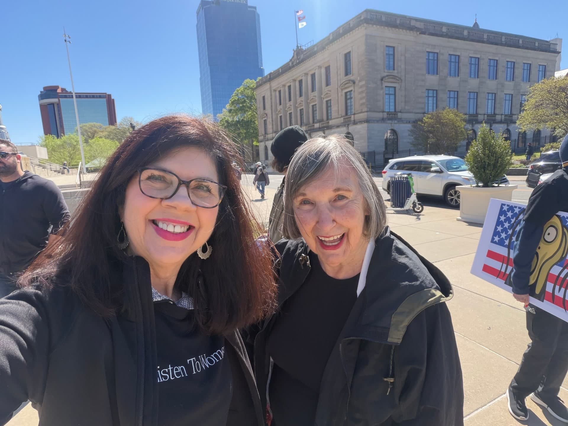 Two women at a rally with listen to women messaging
