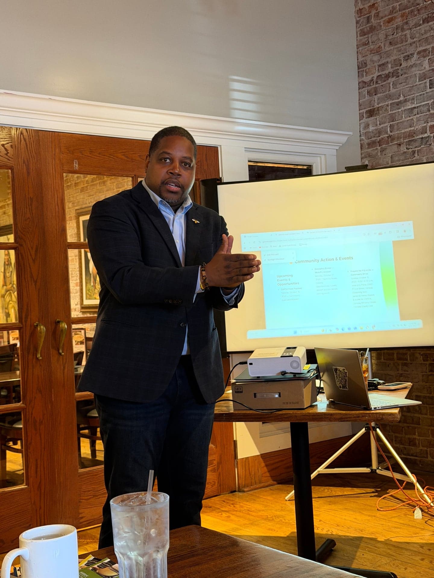 Speaker presenting Community Action & Events on screen at a local meeting